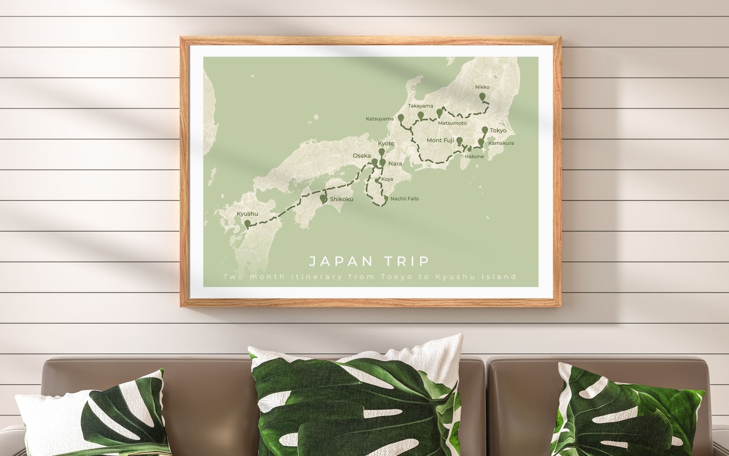 Póster enmarcado que muestra un itinerario de road trip por Japón, en un interior con tonos verdes y madera clara